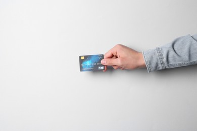 Photo of Man holding credit card on light grey background, closeup