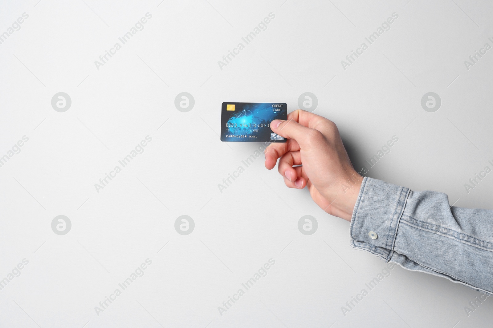 Photo of Man holding credit card on light grey background, closeup