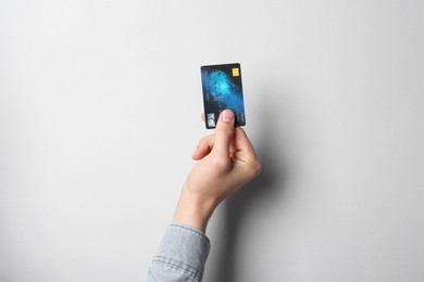 Man holding credit card on light grey background, closeup