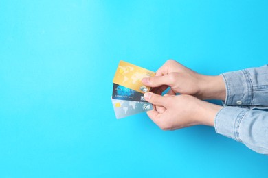 Photo of Man holding credit cards on light blue background, closeup