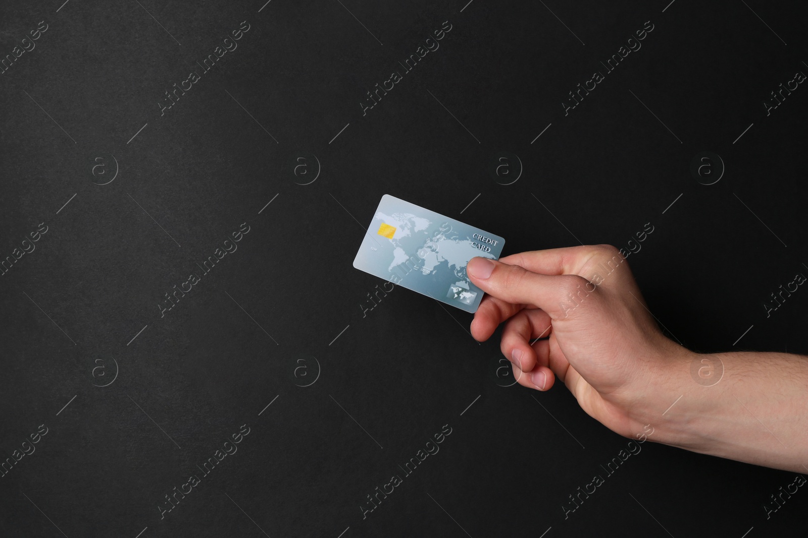 Photo of Man holding credit card on black background, closeup