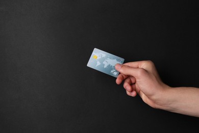 Man holding credit card on black background, closeup