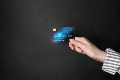 Photo of Woman holding credit card on black background, closeup