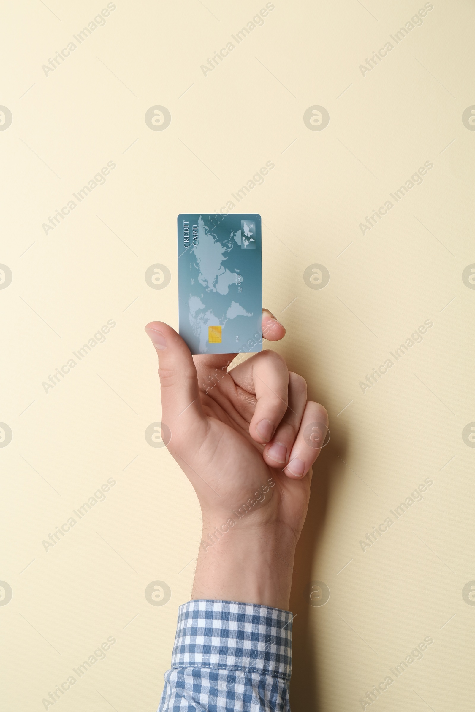 Photo of Man holding credit card on beige background, closeup