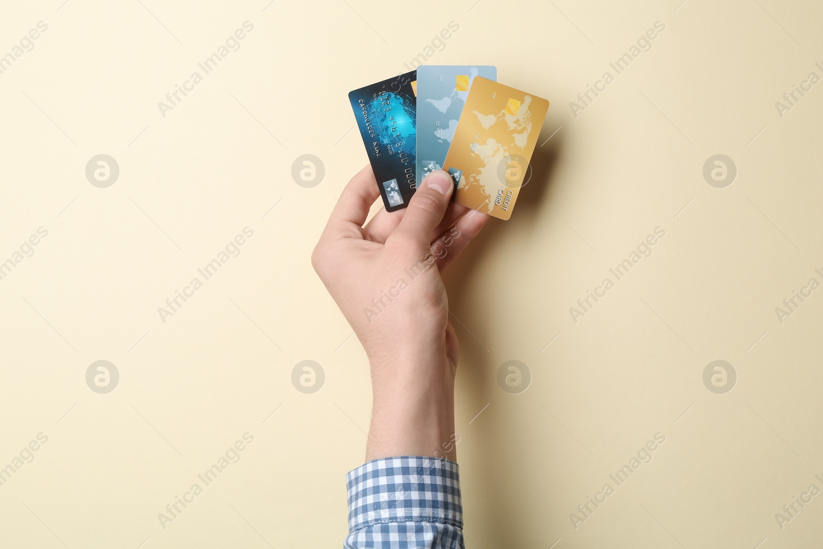 Photo of Man holding credit cards on beige background, closeup