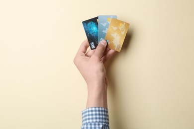 Photo of Man holding credit cards on beige background, closeup