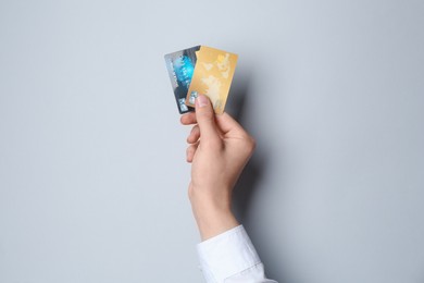 Man holding credit cards on light grey background, closeup