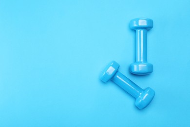 Two dumbbells on light blue background, top view. Space for text