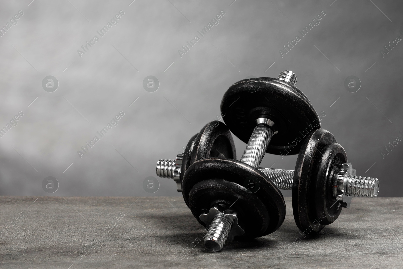 Photo of Two barbells on grey textured table. Space for text