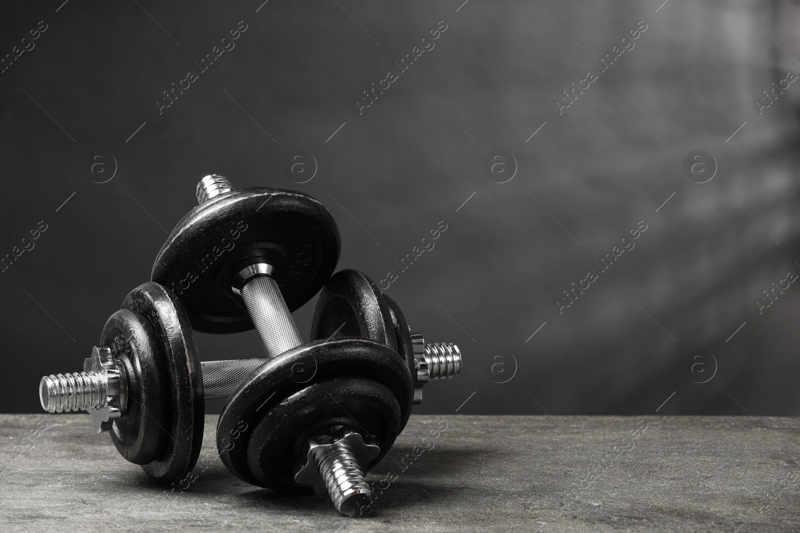 Photo of Two barbells on grey textured table. Space for text