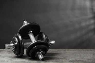 Photo of Two barbells on grey textured table. Space for text