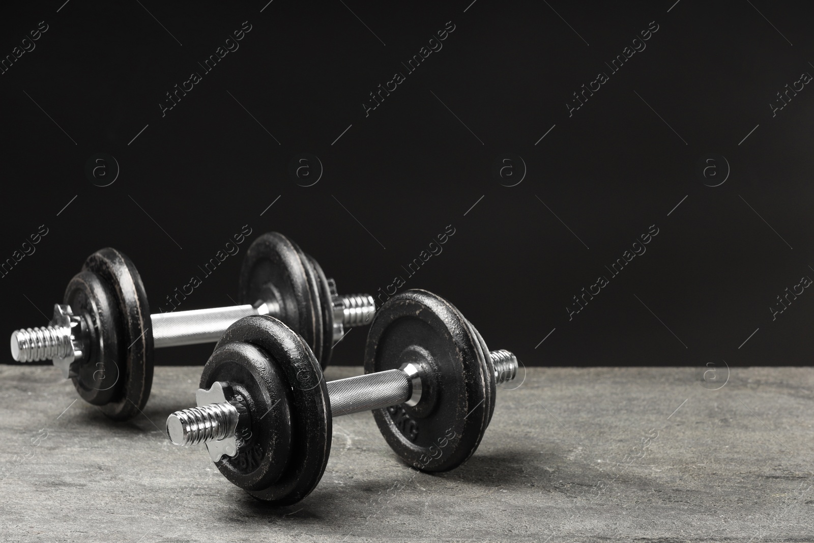 Photo of Two barbells on grey textured table, closeup. Space for text