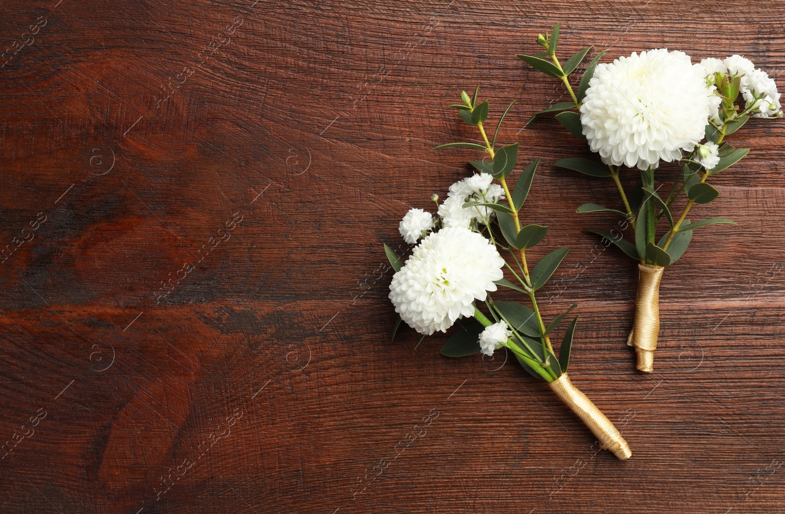 Photo of Small stylish boutonnieres on wooden table, top view. Space for text