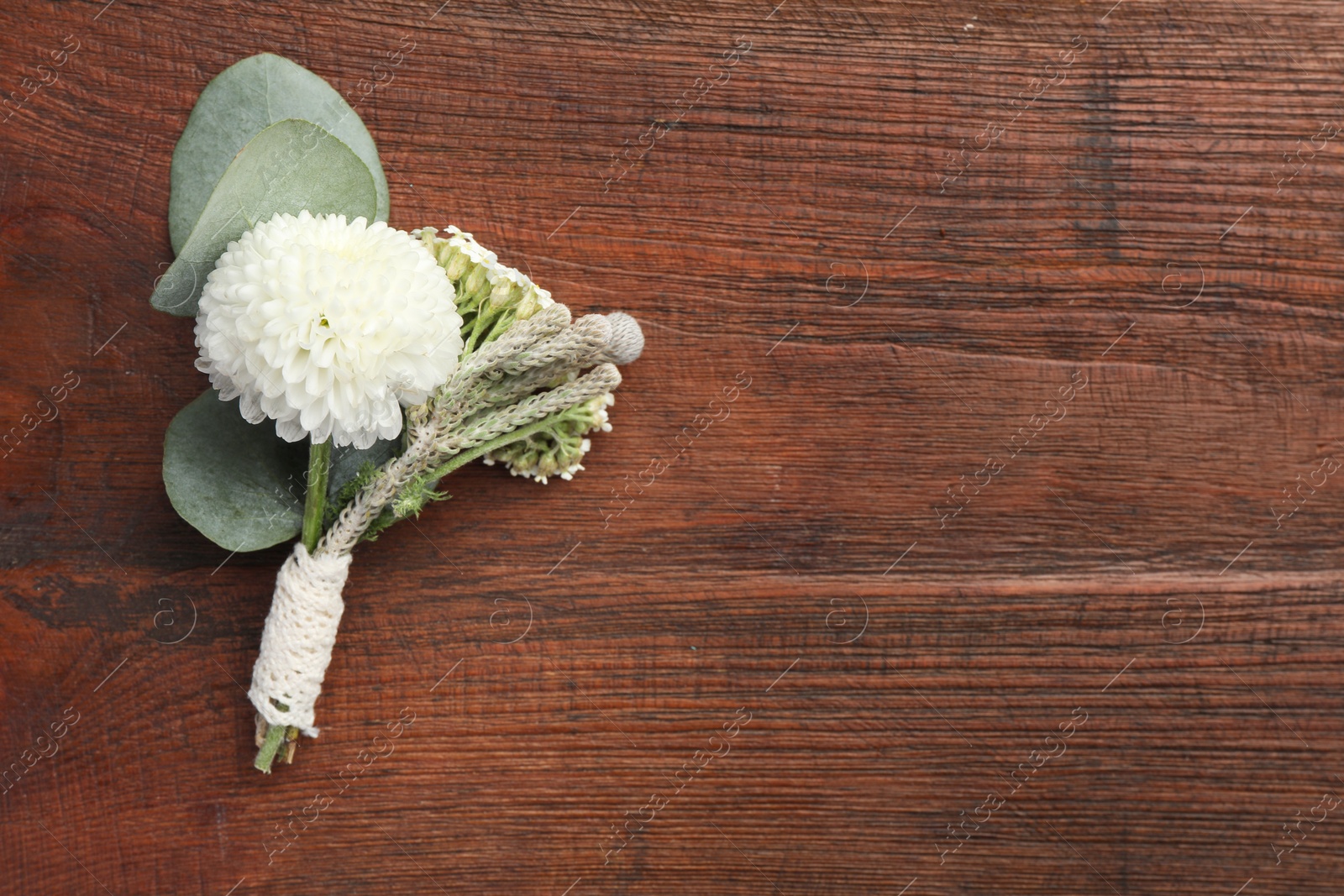 Photo of Small stylish boutonniere on wooden table, top view. Space for text