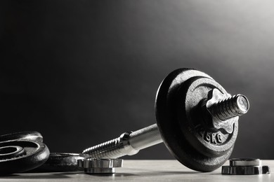 Parts of barbell on light table against dark background