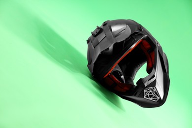 Photo of Modern motorcycle helmet with visor on light green background. Space for text