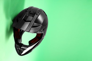 Photo of Modern motorcycle helmet with visor on light green background. Space for text