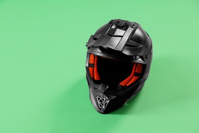 Photo of Modern motorcycle helmet with visor on light green background. Space for text