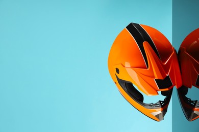 Photo of Modern motorcycle helmet with visor on mirror surface against light blue background. Space for text