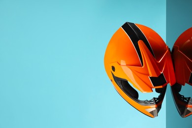 Modern motorcycle helmet with visor on mirror surface against light blue background. Space for text