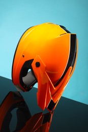 Modern motorcycle helmet with visor on mirror surface against light blue background