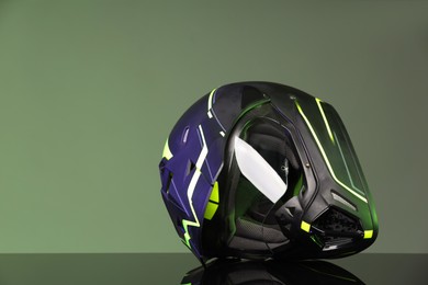 Photo of Modern motorcycle helmet with visor on mirror surface against grey background. Space for text