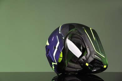 Modern motorcycle helmet with visor on mirror surface against grey background. Space for text