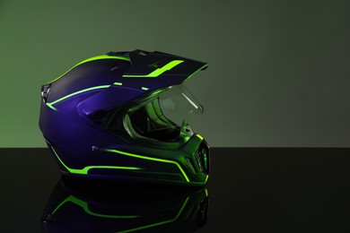 Modern motorcycle helmet with visor on mirror surface against grey background. Space for text