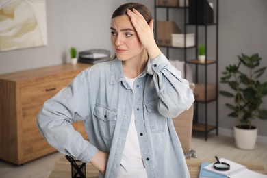 Photo of Embarrassed woman in denim jacket near table in office