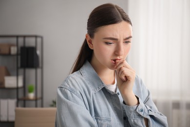 Photo of Embarrassed woman in denim jacket in office, space for text