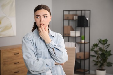Photo of Embarrassed woman in denim jacket in office, space for text