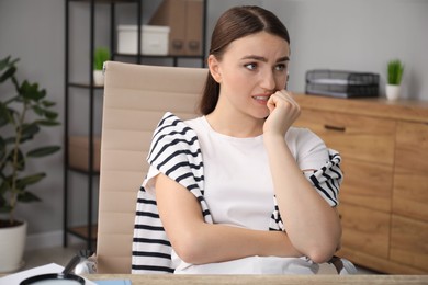 Photo of Embarrassed woman at wooden table in office