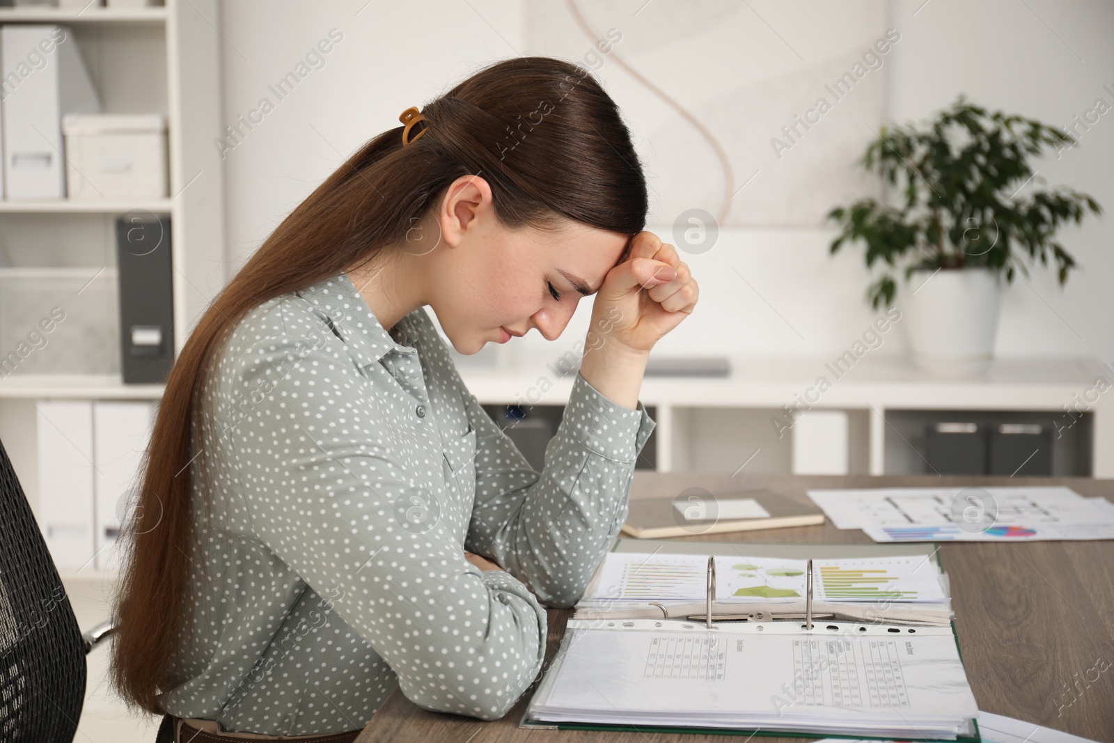 Photo of Embarrassed woman at wooden table with documents in office, space for text