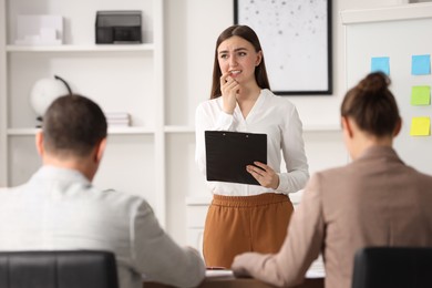 Photo of Woman with clipboard feeling embarrassed during business meeting in office