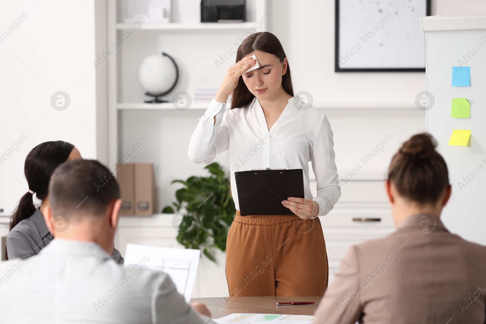 Photo of Woman with clipboard feeling embarrassed during business meeting in office