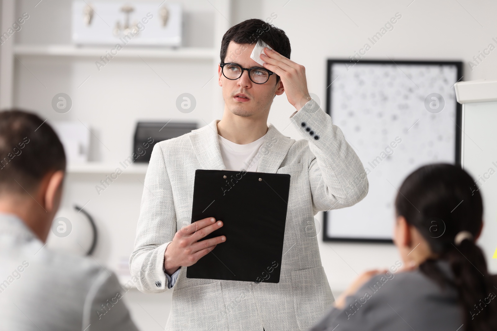 Photo of Man with clipboard feeling embarrassed during business meeting in office