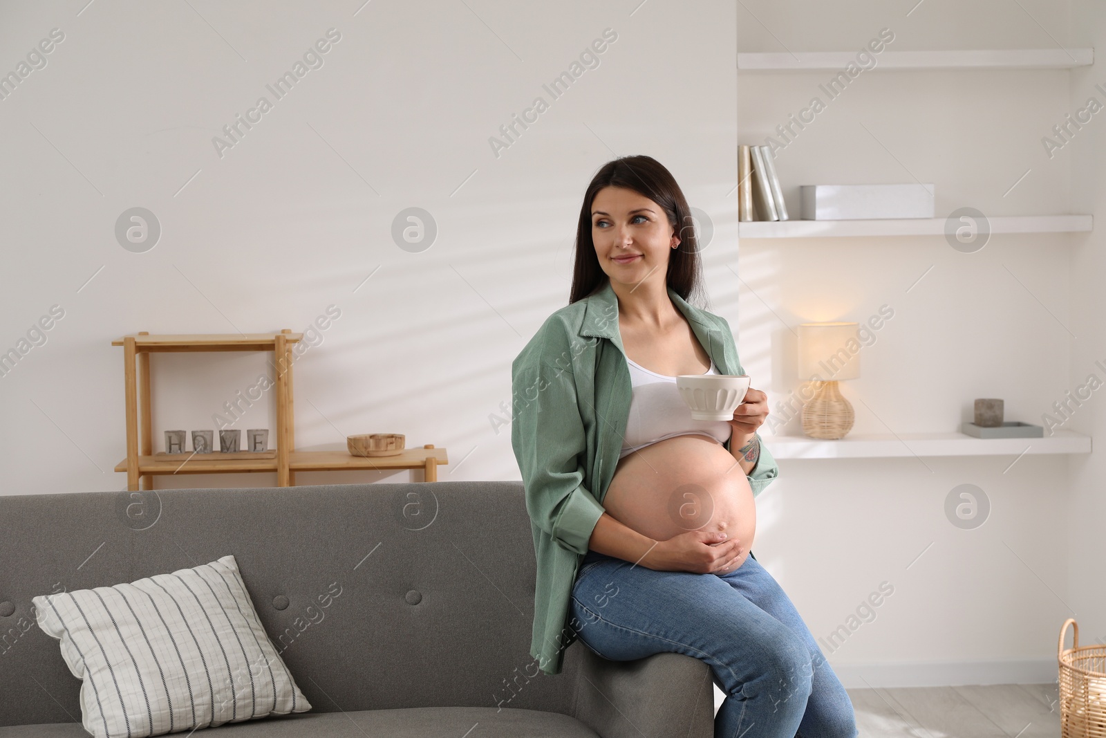 Photo of Beautiful pregnant woman sitting on sofa at home