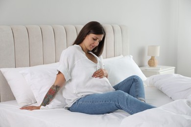 Photo of Beautiful pregnant woman on bed at home