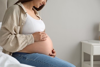 Photo of Pregnant woman on bed at home, closeup. Space for text