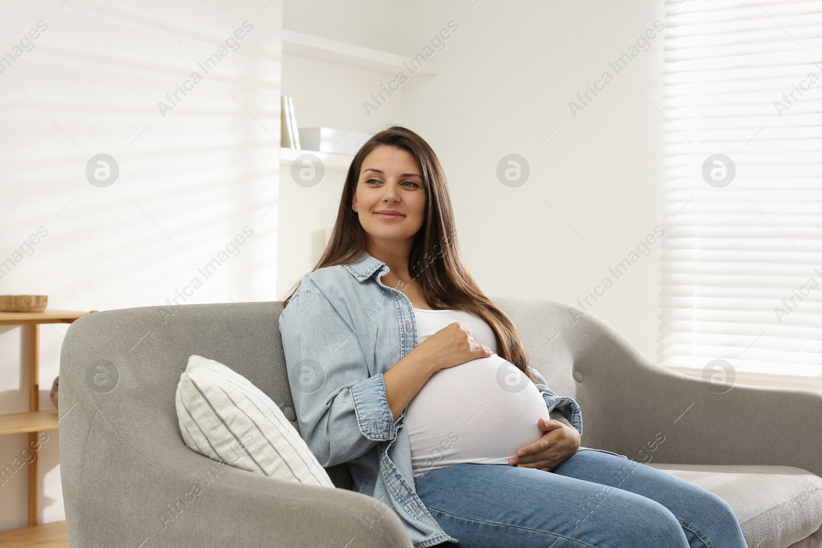 Photo of Beautiful pregnant woman sitting on sofa at home