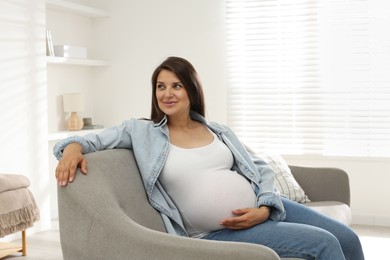 Photo of Beautiful pregnant woman sitting on sofa at home