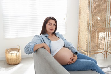 Beautiful pregnant woman sitting on sofa at home