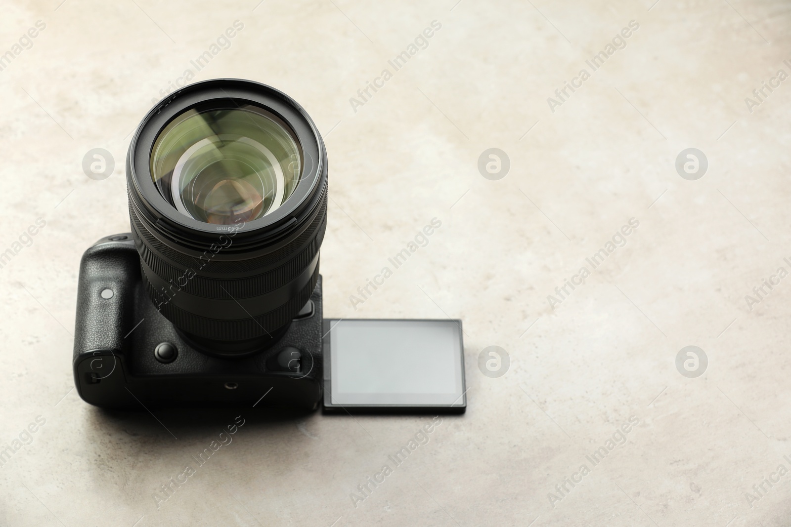 Photo of Modern photo camera on light grey table, space for text