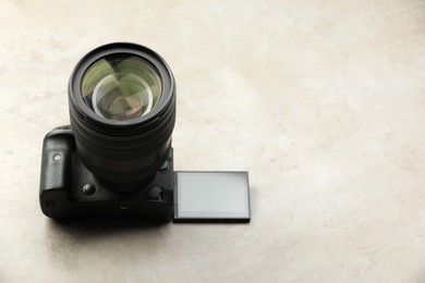 Modern photo camera on light grey table, space for text