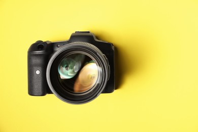 Photo of One modern photo camera on yellow background, top view. Space for text