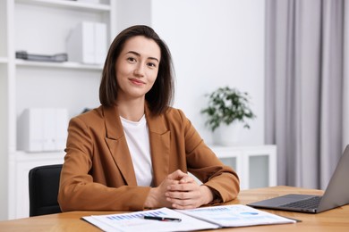 Photo of Consultant at table with documents and laptop in office