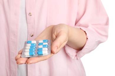 Photo of Woman holding blister with antibiotic pills on white background, closeup