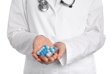 Photo of Doctor holding blister with antibiotic pills on white background, closeup