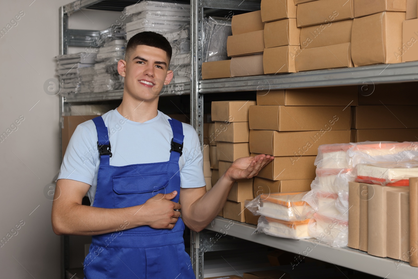 Photo of Smiling young man near many cardboard boxes in auto store