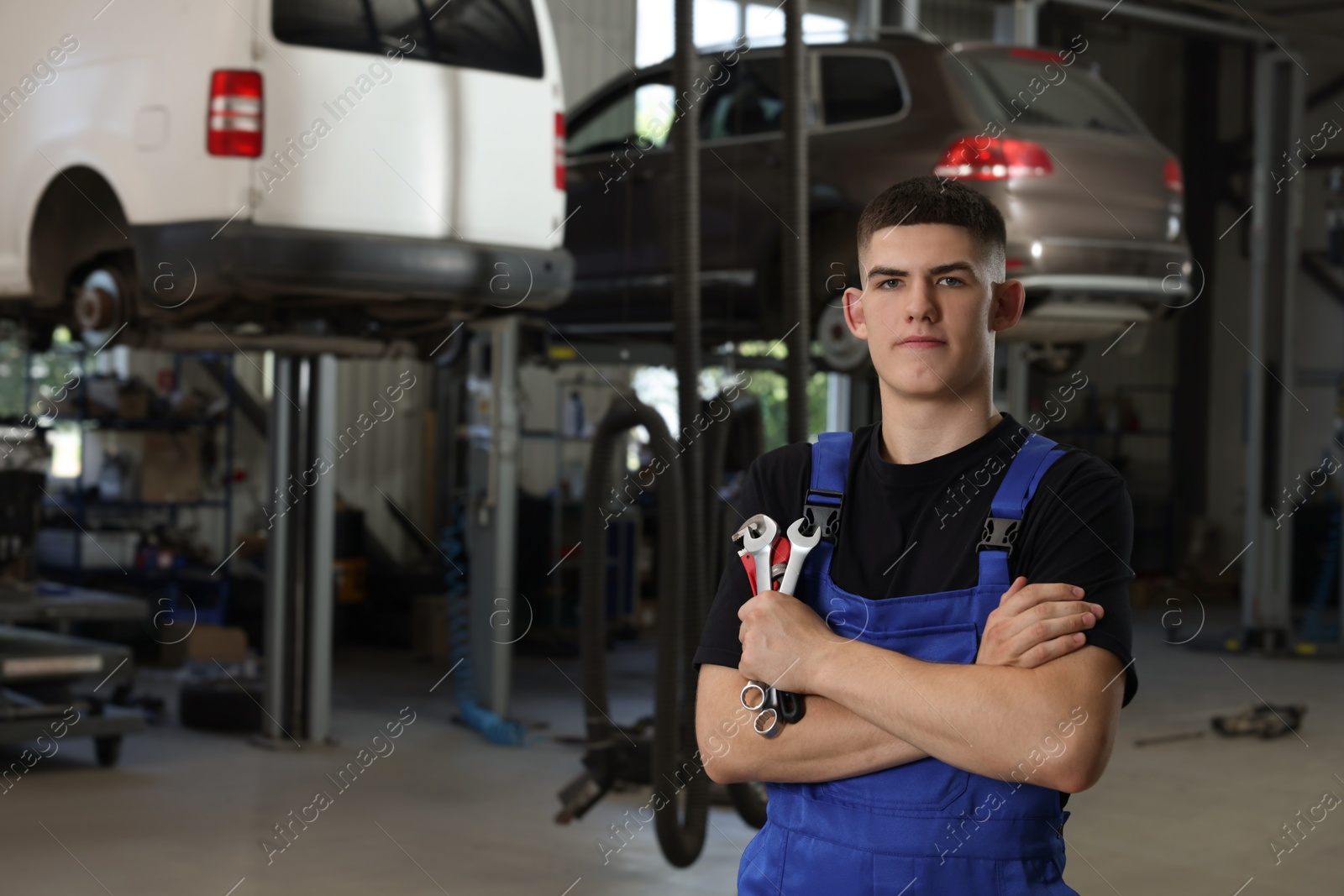 Photo of Young auto mechanic with wrenches at automobile repair shop